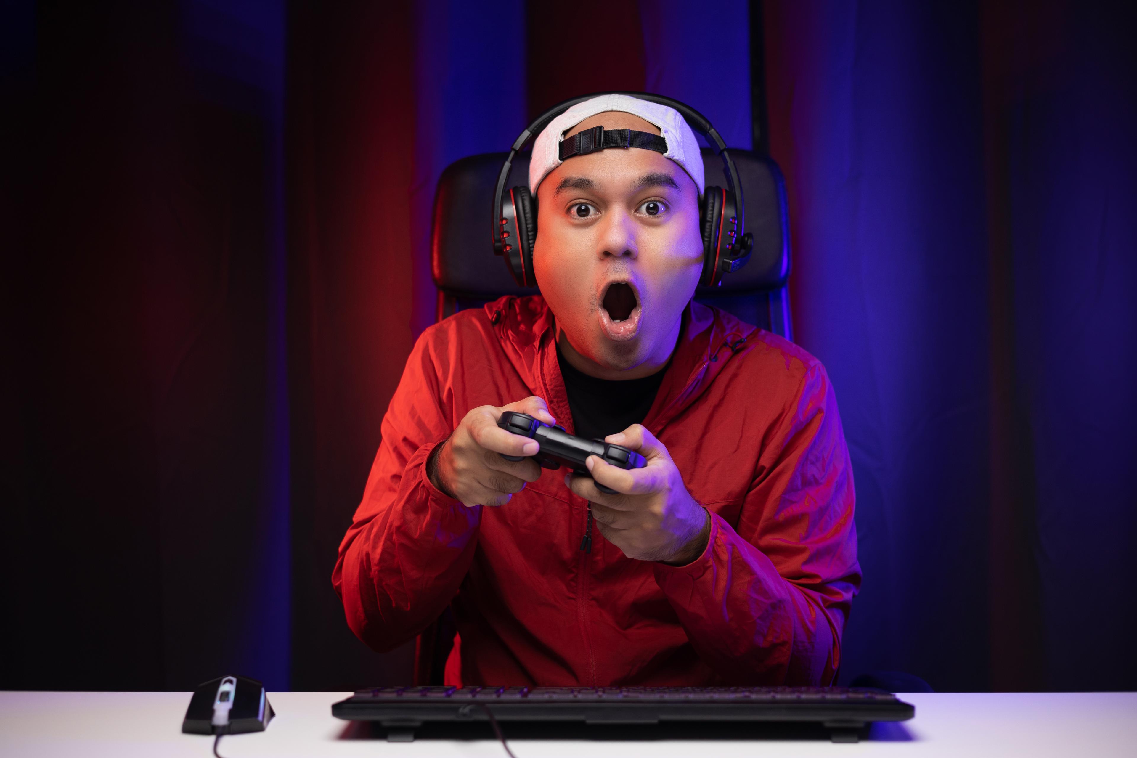 A gamer looks excited while enjoying their gaming chair, laptop and accessories.